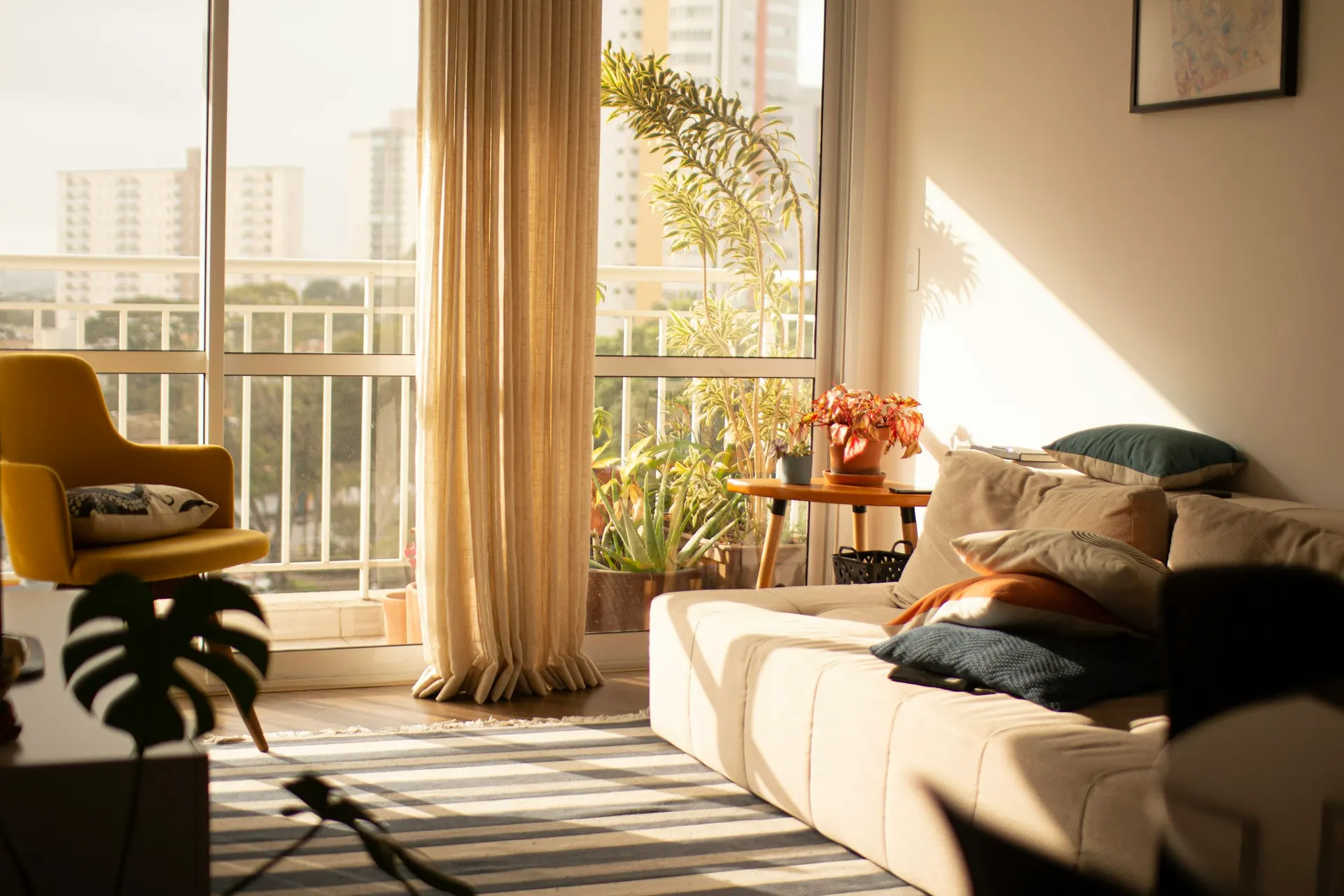 Living luminoso con cortinas de lino, plantas y un ventanal a la ciudad